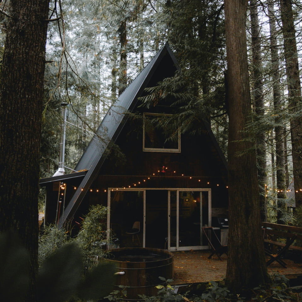 Pequena casa de madeira azul escuro, conhecida como Sapphire, em meio à floresta